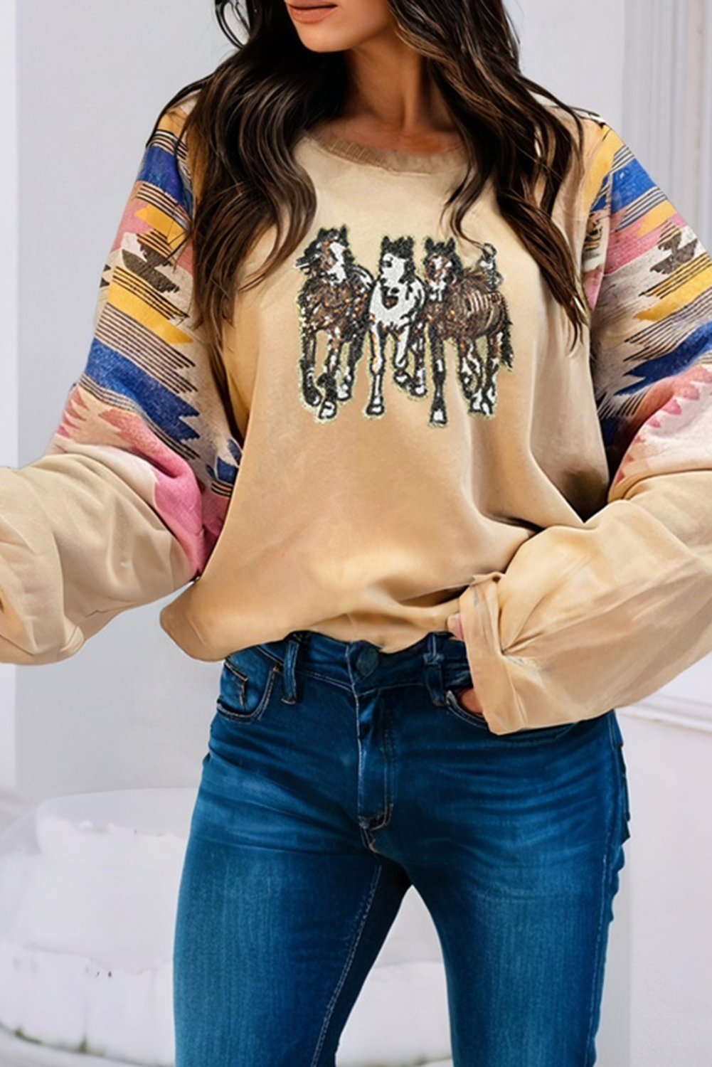 Beige sweatshirt with horse graphic and colorful sleeves worn by a person, against a white background.