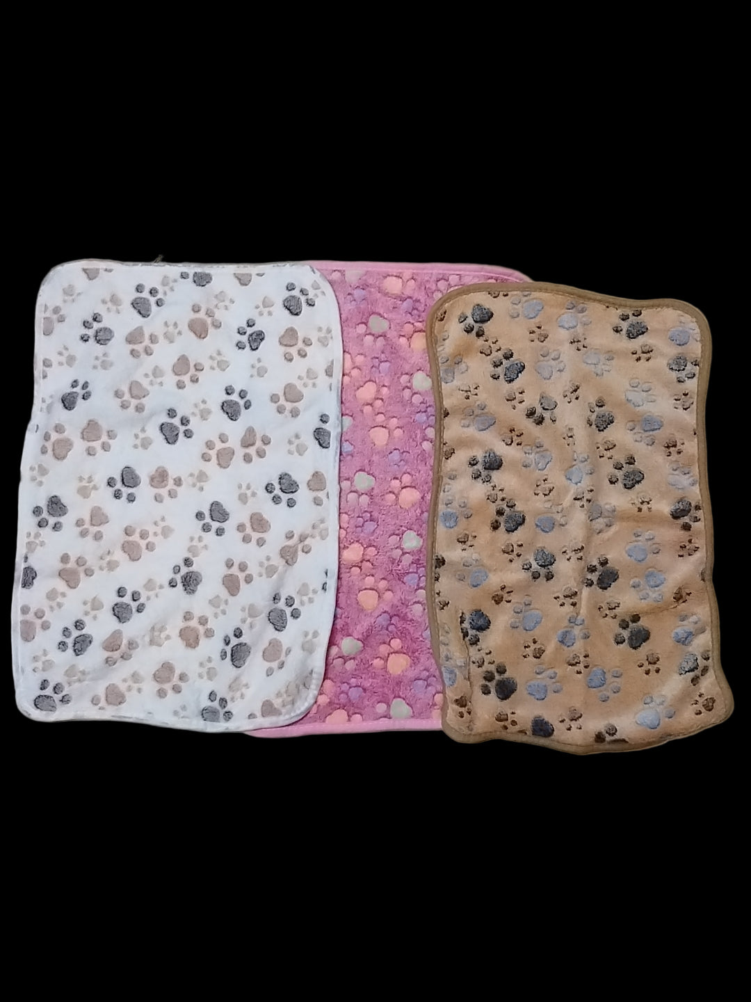 Three pet blankets with paw print patterns on a tiled floor.
