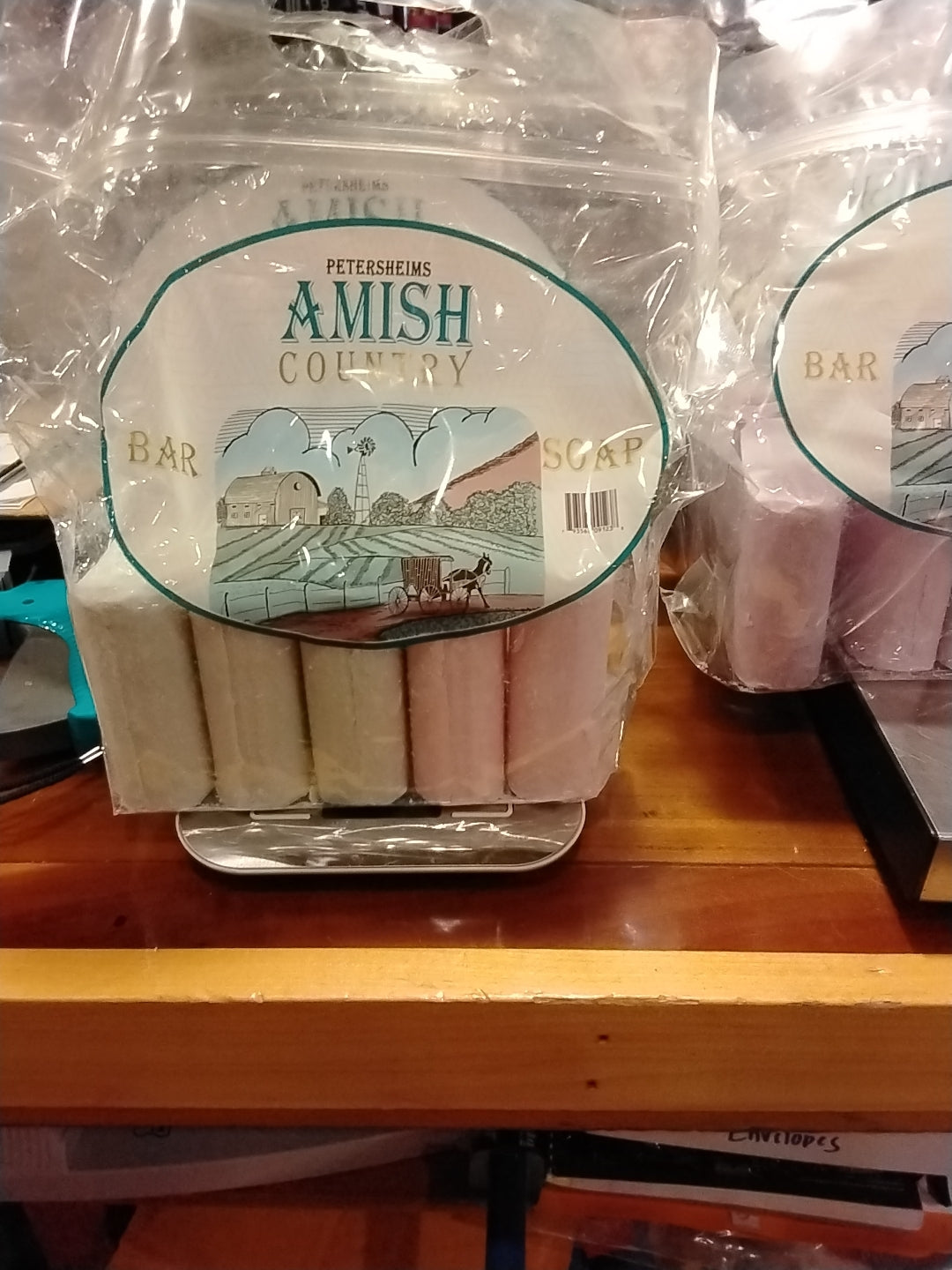 Packaged bar soap with 'Amish Country' branding, displayed in a clear plastic container with a label showcasing a barn and a horse.