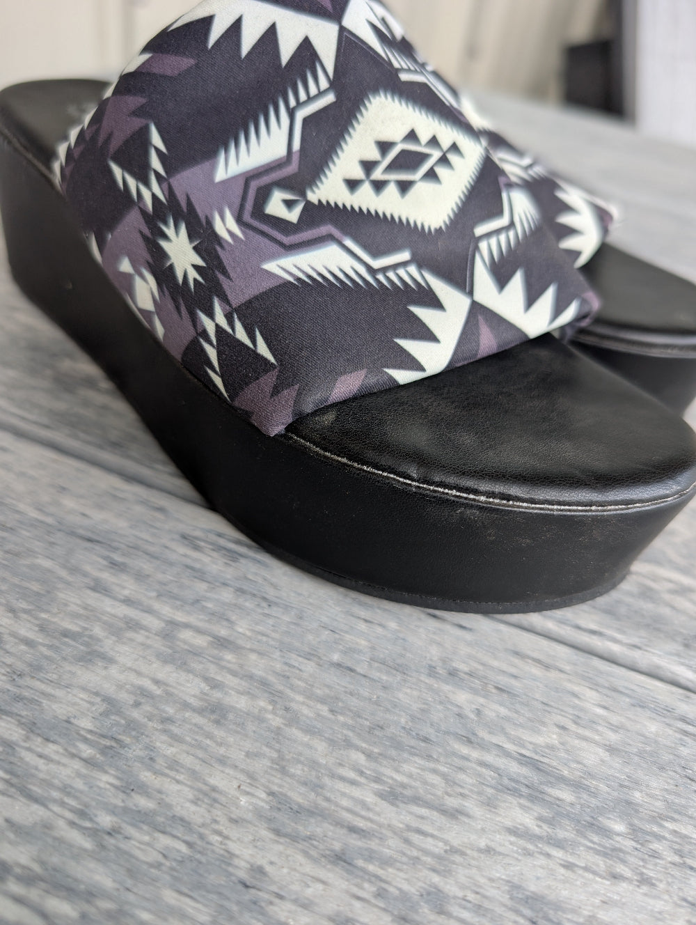 Black sandal with a patterned insole on a gray surface