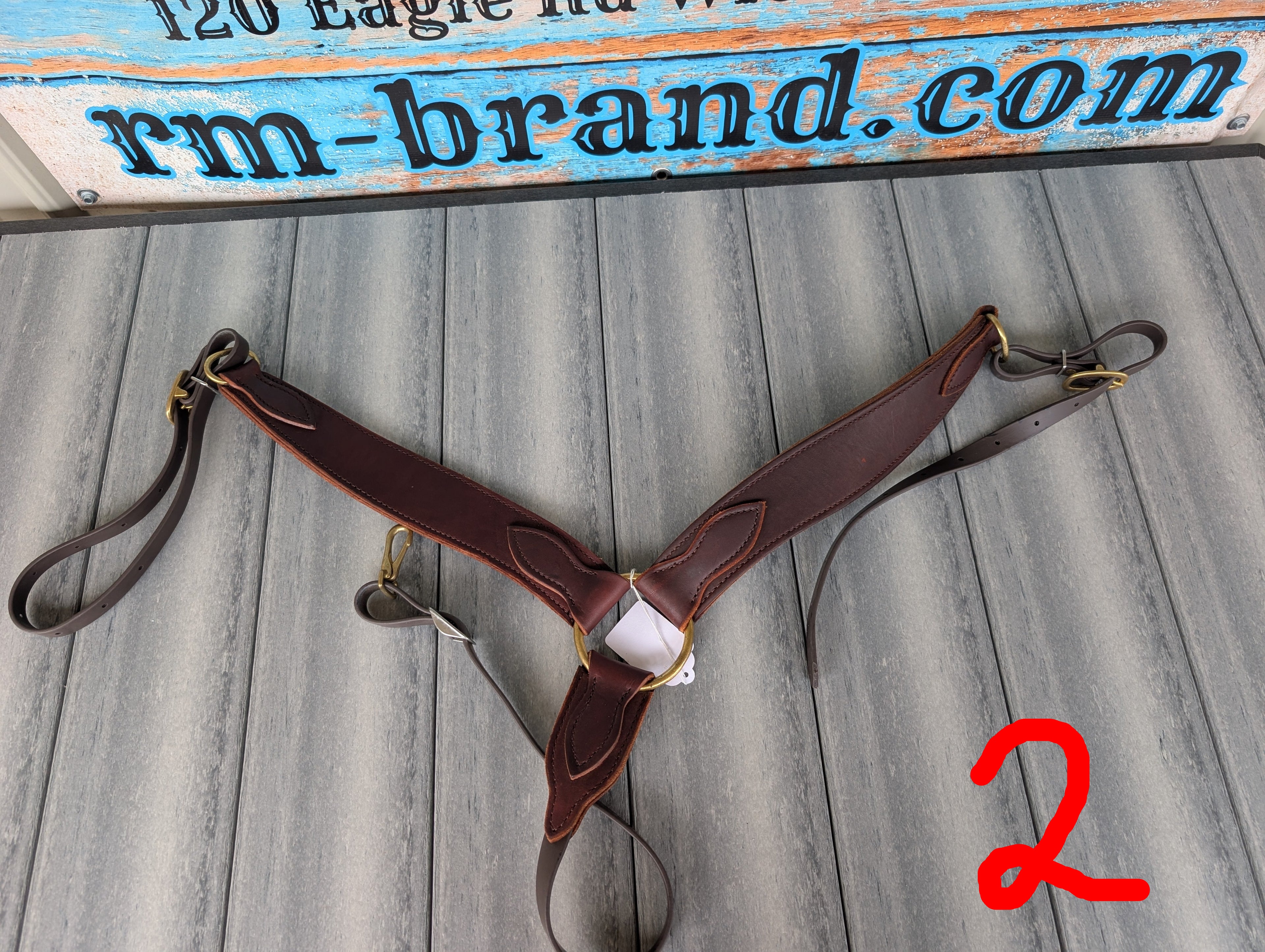 Brown leather harness on a wooden surface with 'rm-brand.com' branding.