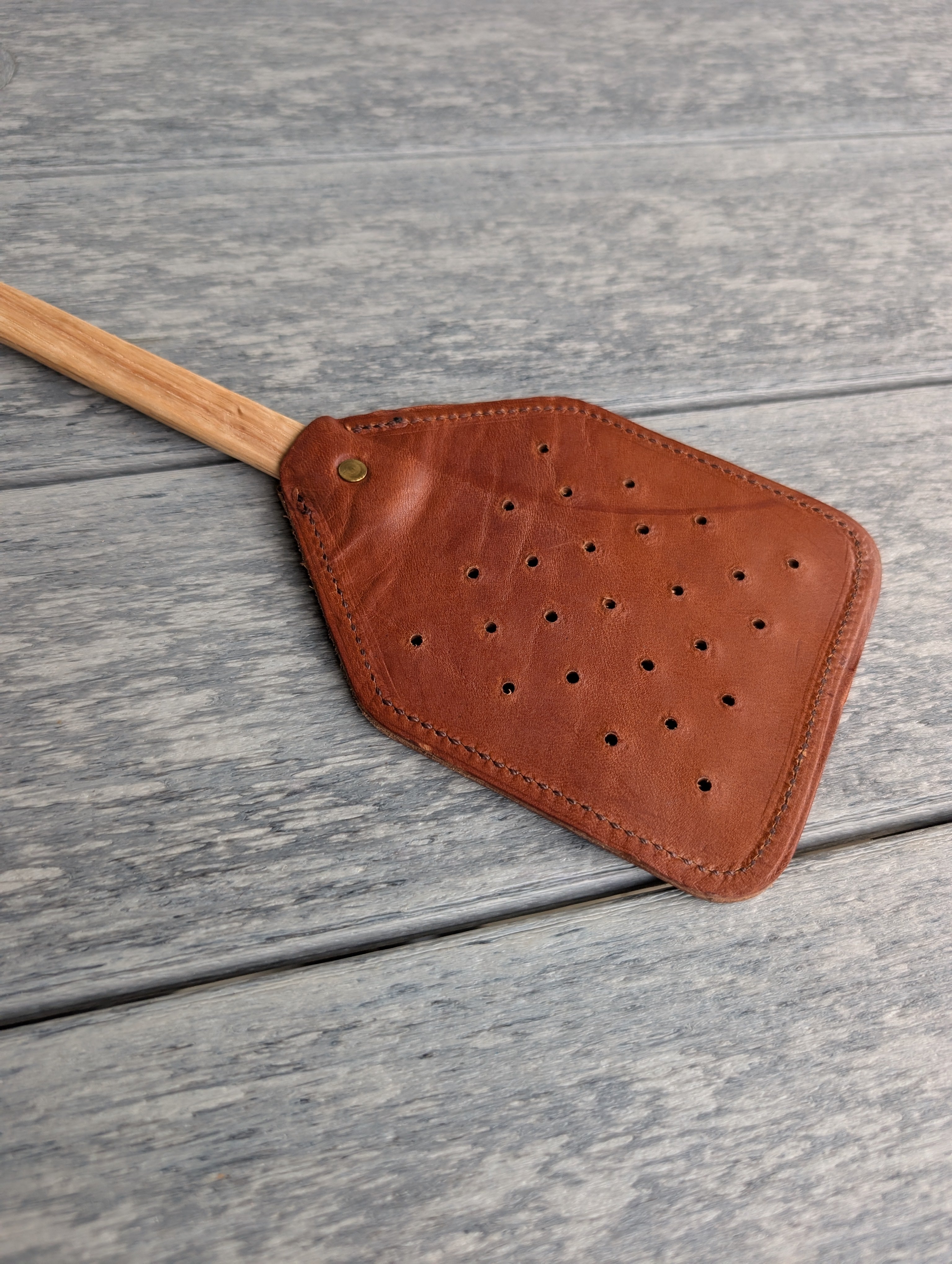 Durable fly swatter made with real leather and a solid wooden grip handle