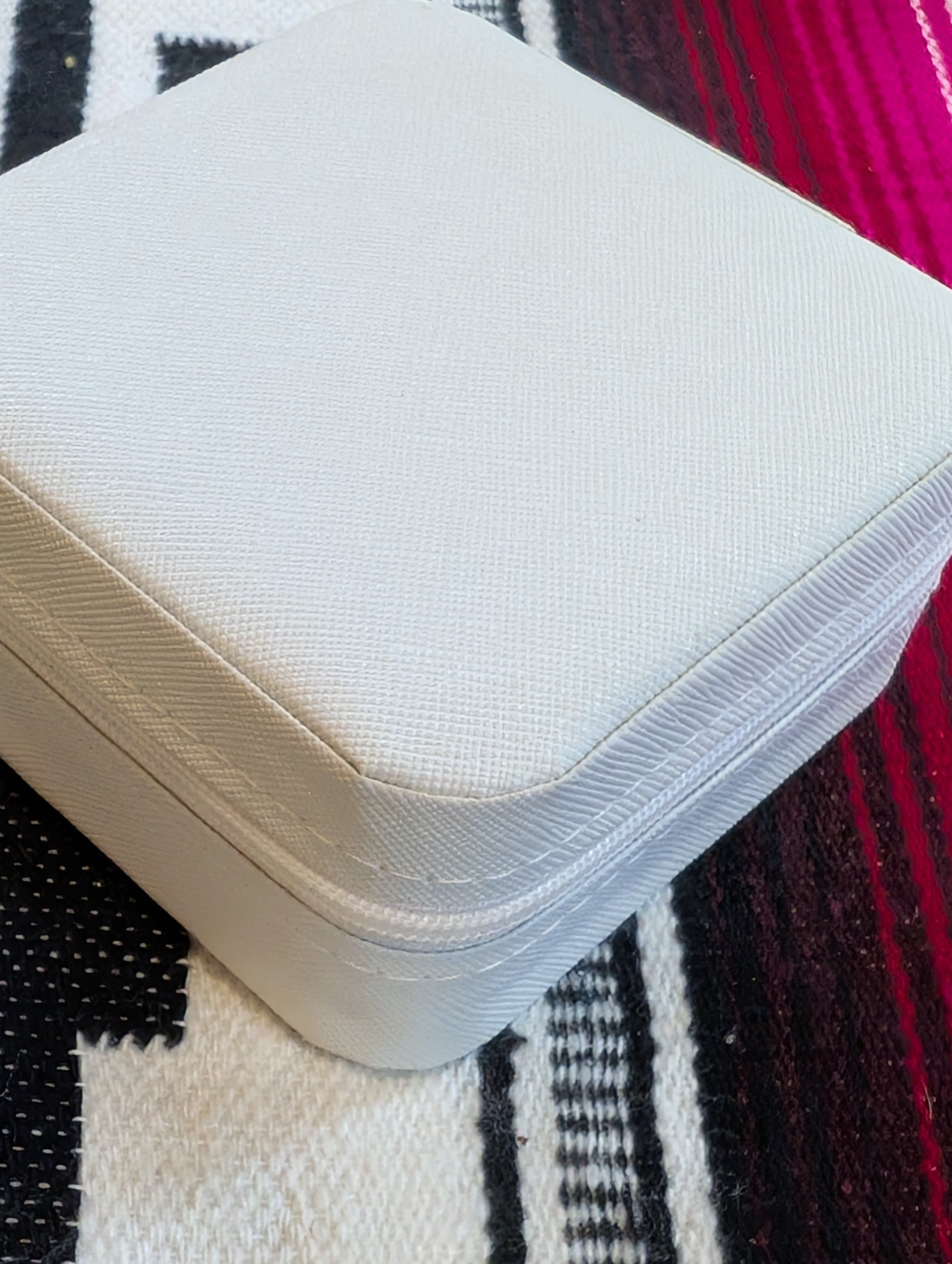 Closed ivory jewelry case next to travel accessories