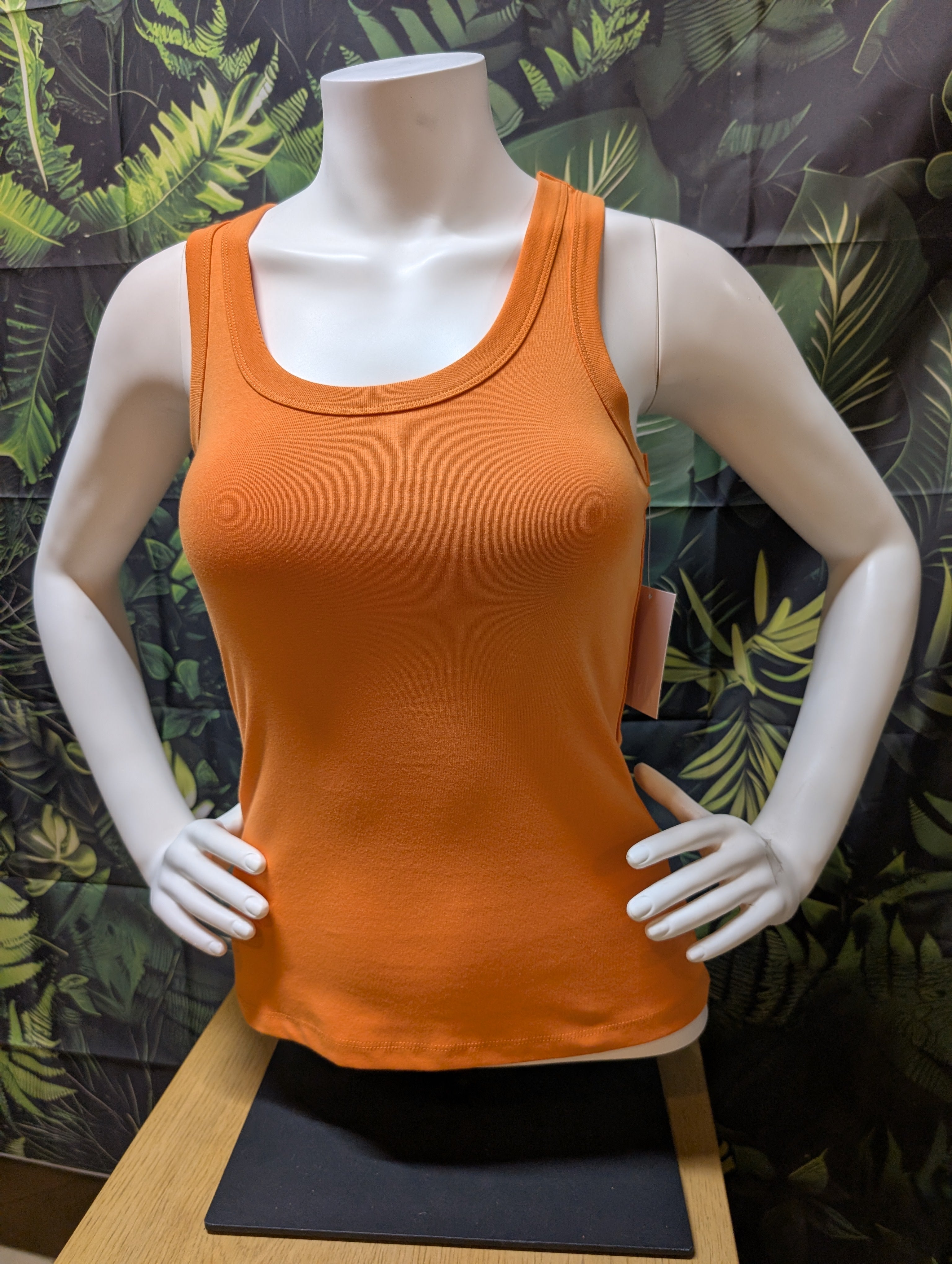 Orange tank top on a mannequin with a leafy background