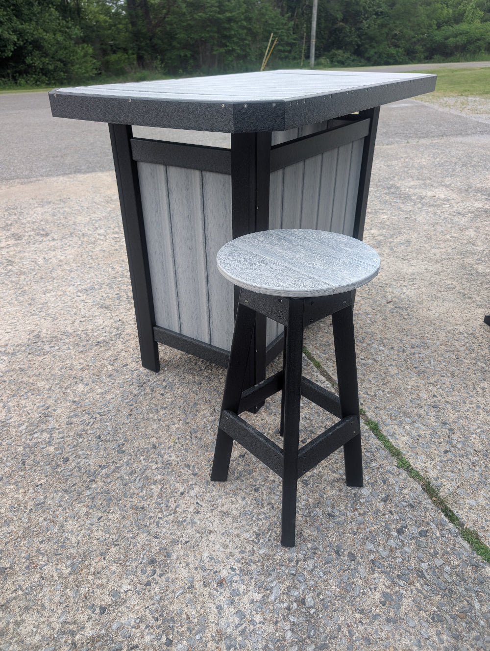 Outdoor bar set with a table and stool on a concrete surface.