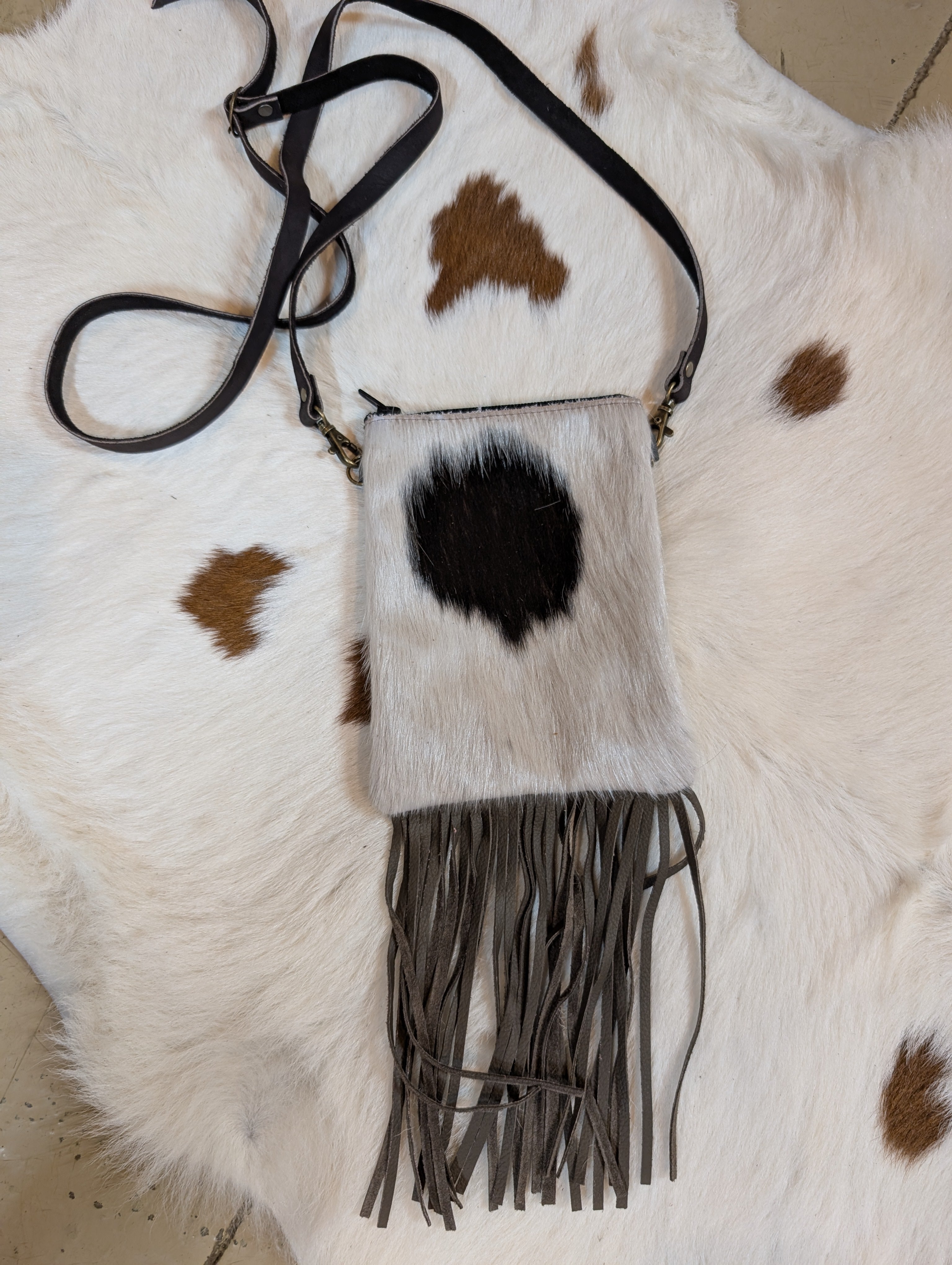 Fur bag with fringes on a cowhide surface