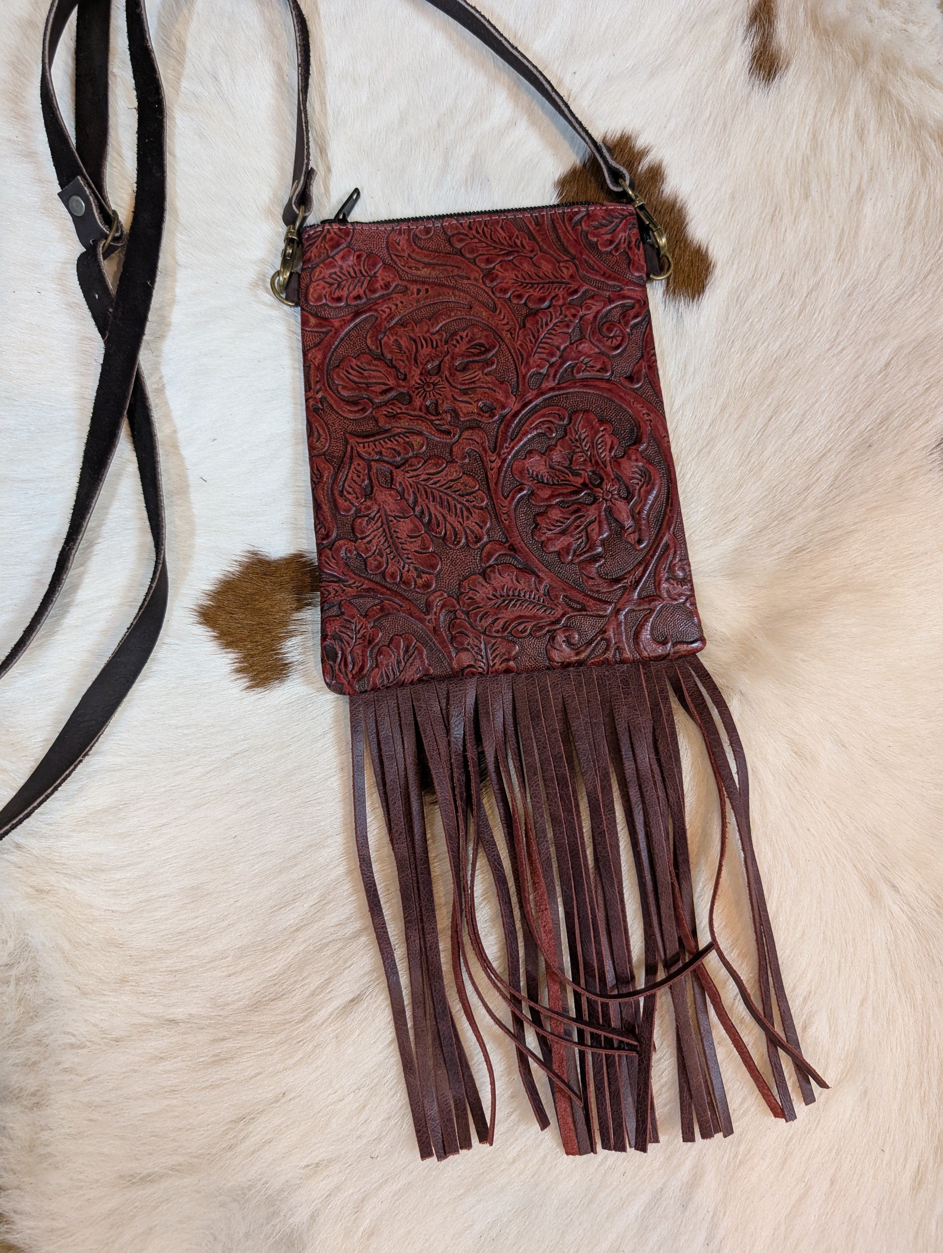 Tooled western design genuine leather fringe crossbody bag with intricate floral patterns and zipper closure.