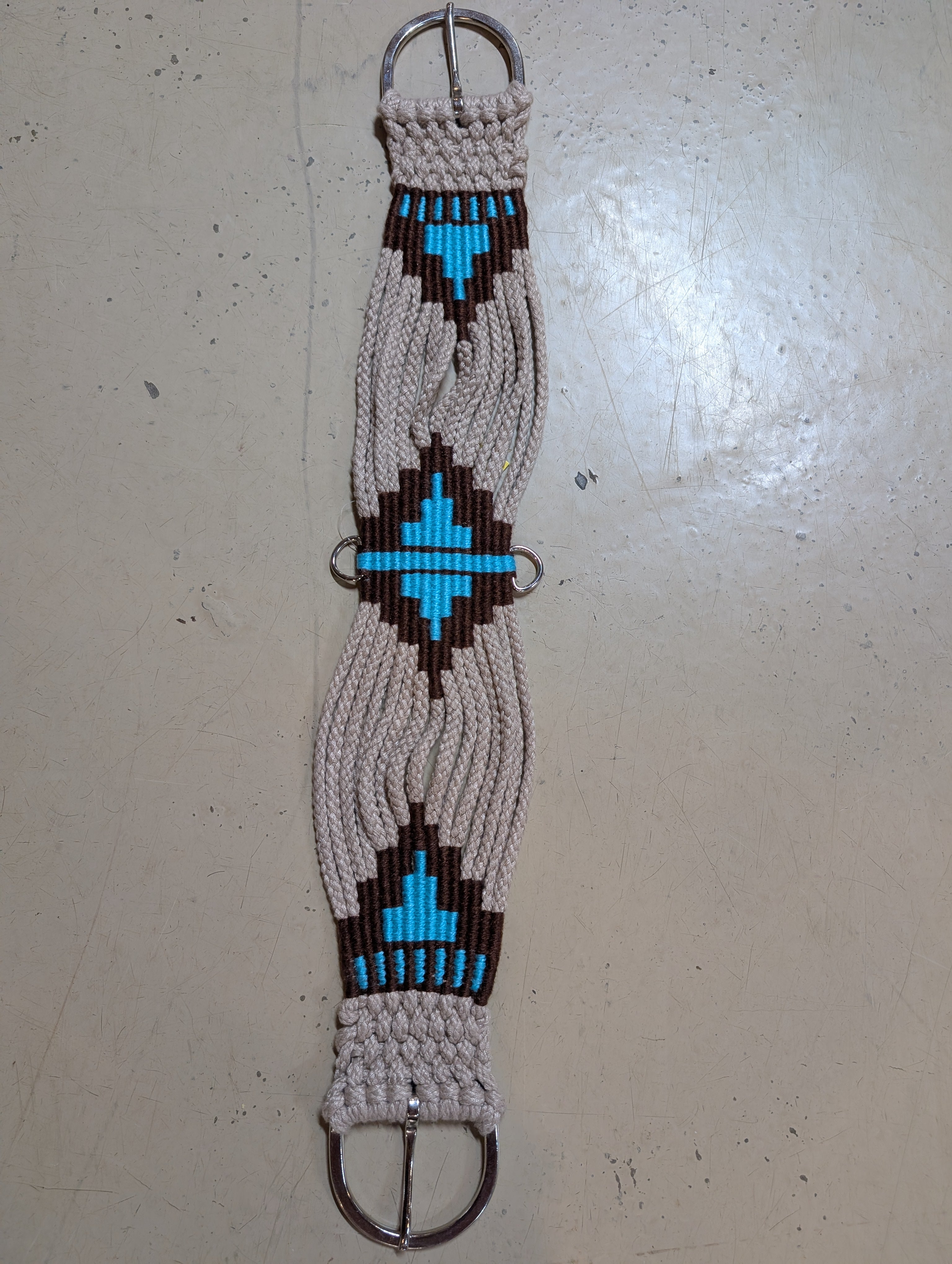 Showman tan multi-strand string girth featuring teal and brown Aztec design with stainless steel hardware