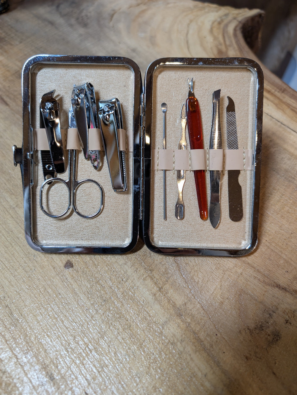 Manicure set with various tools in an open case on a wooden surface