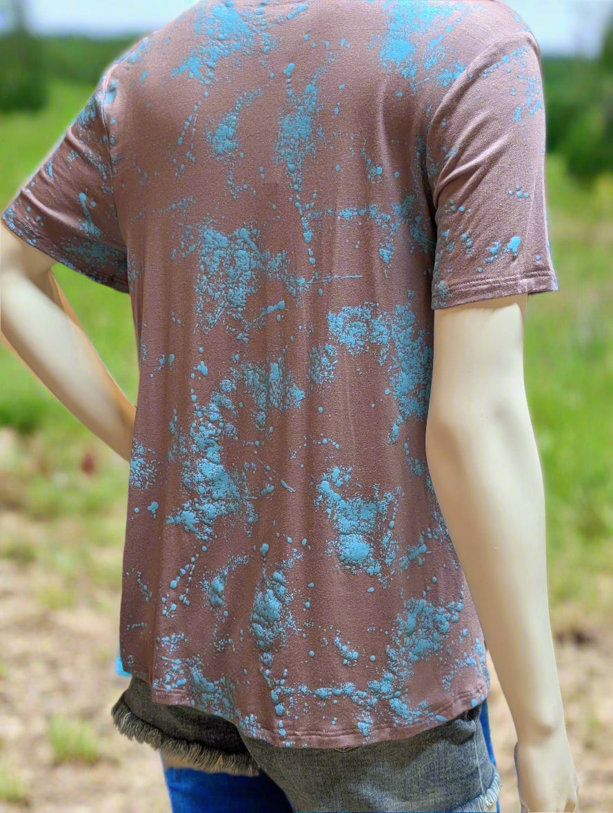 Close-up of teal Western fringe top showing V-neckline, metallic studs, and flowing fabric details.