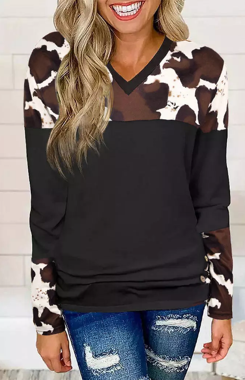 Woman wearing a black sweater with cow print sleeves and a V-neck