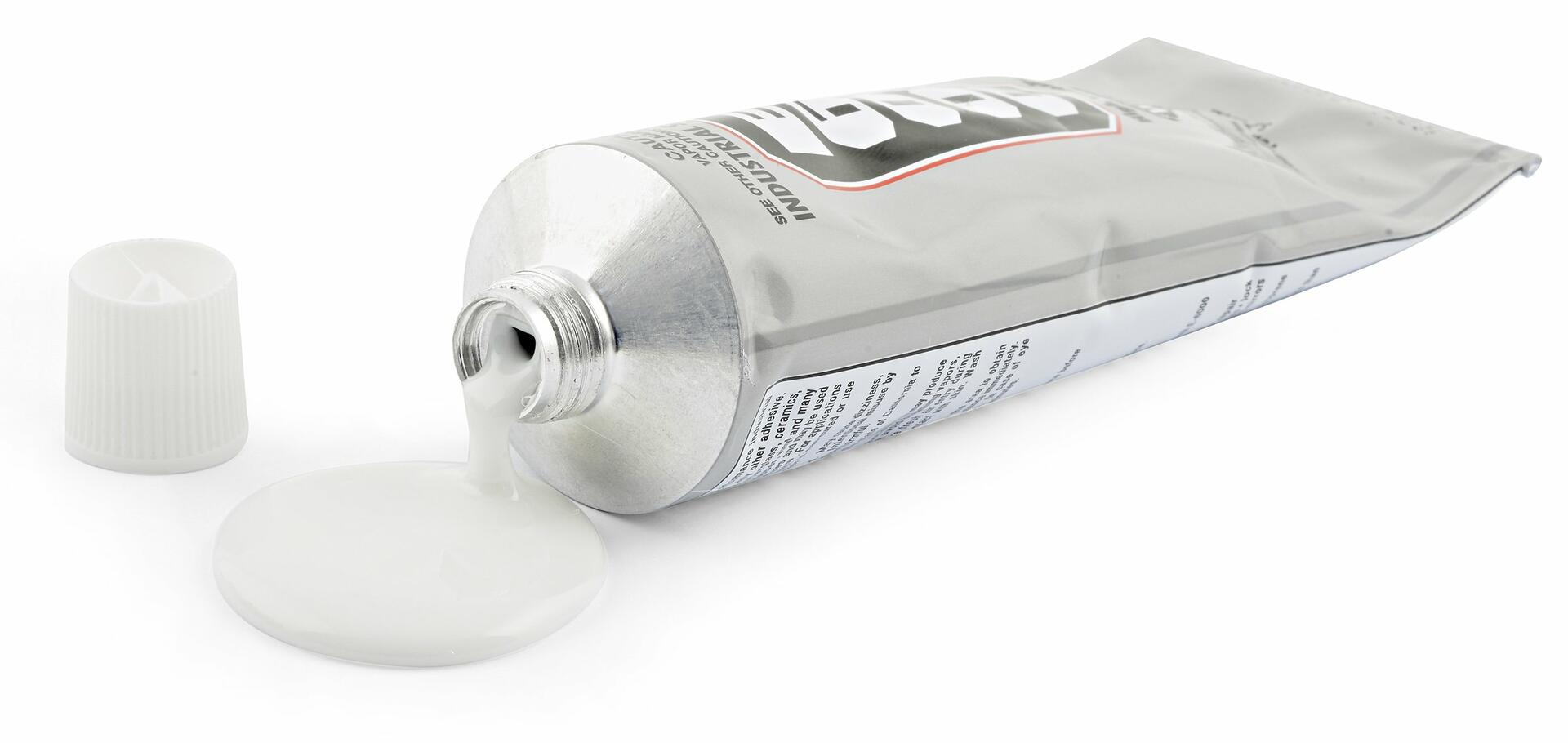 Open tube of white adhesive with a label on a white background