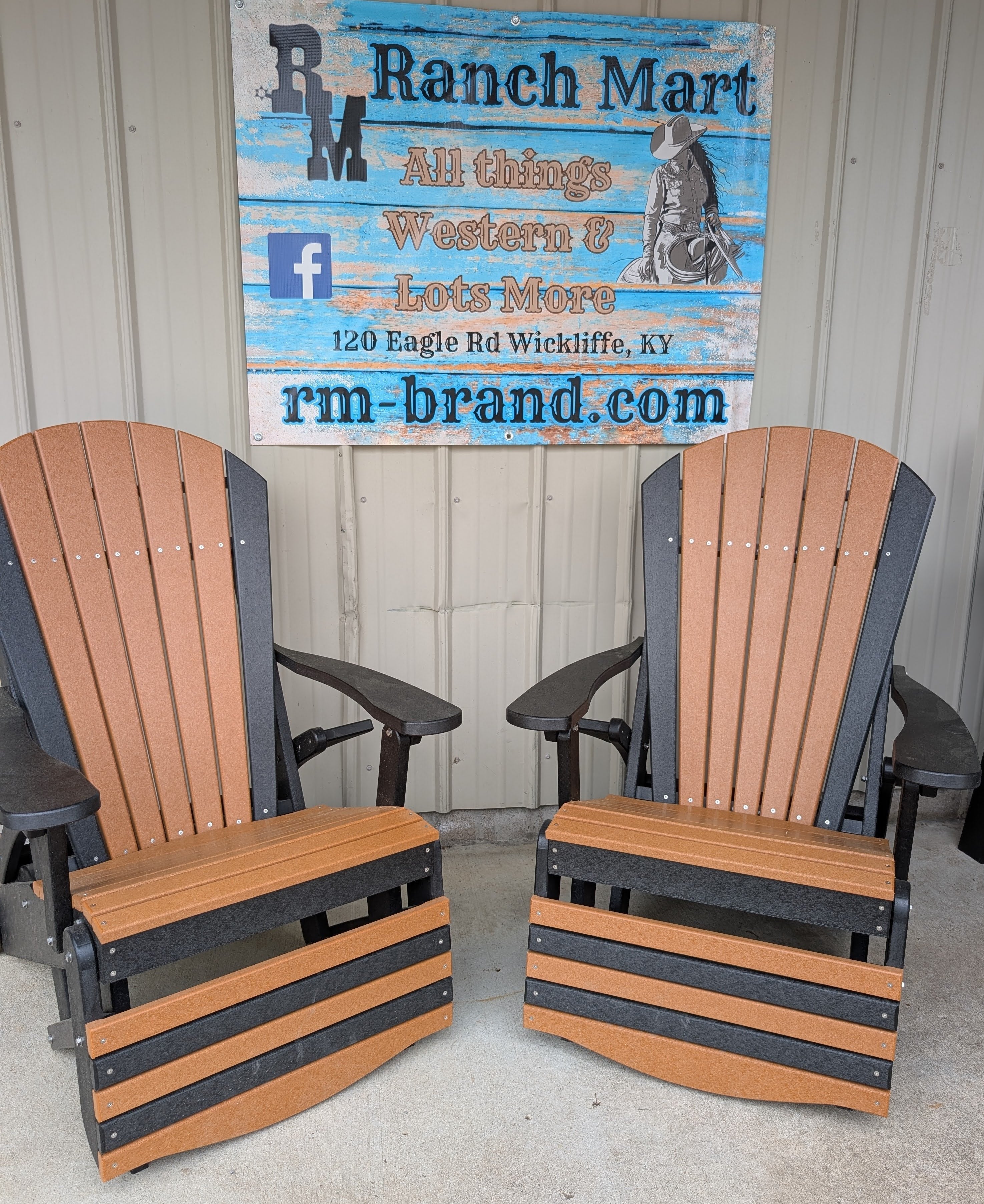 Two cedar and black poly outdoor reclining Adirondack chairs sitting on a concrete patio in front of a Ranch Mart storefront sign.