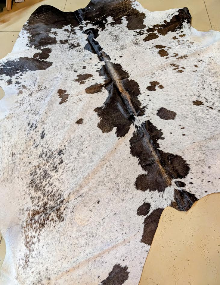 Cowhide rug with a distinctive pattern on a beige floor.