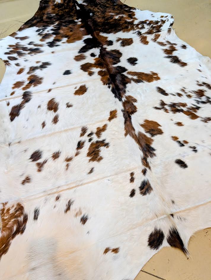 Cowhide rug with brown and black patches on a beige floor.