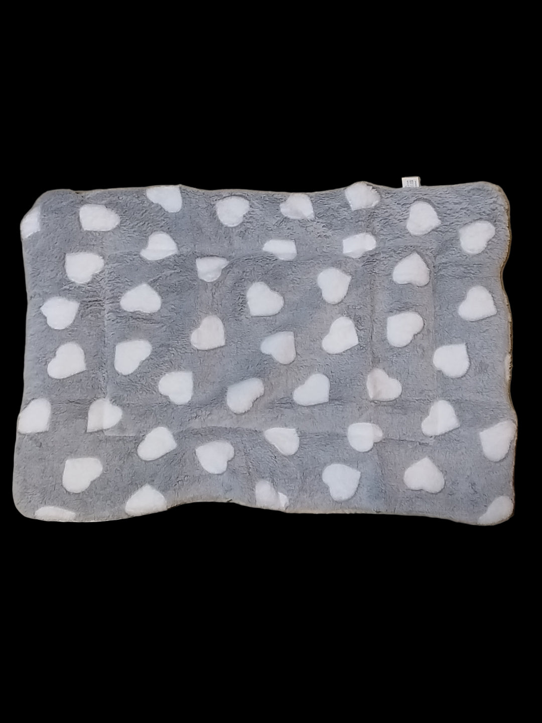 Gray blanket with white heart patterns on a beige floor.