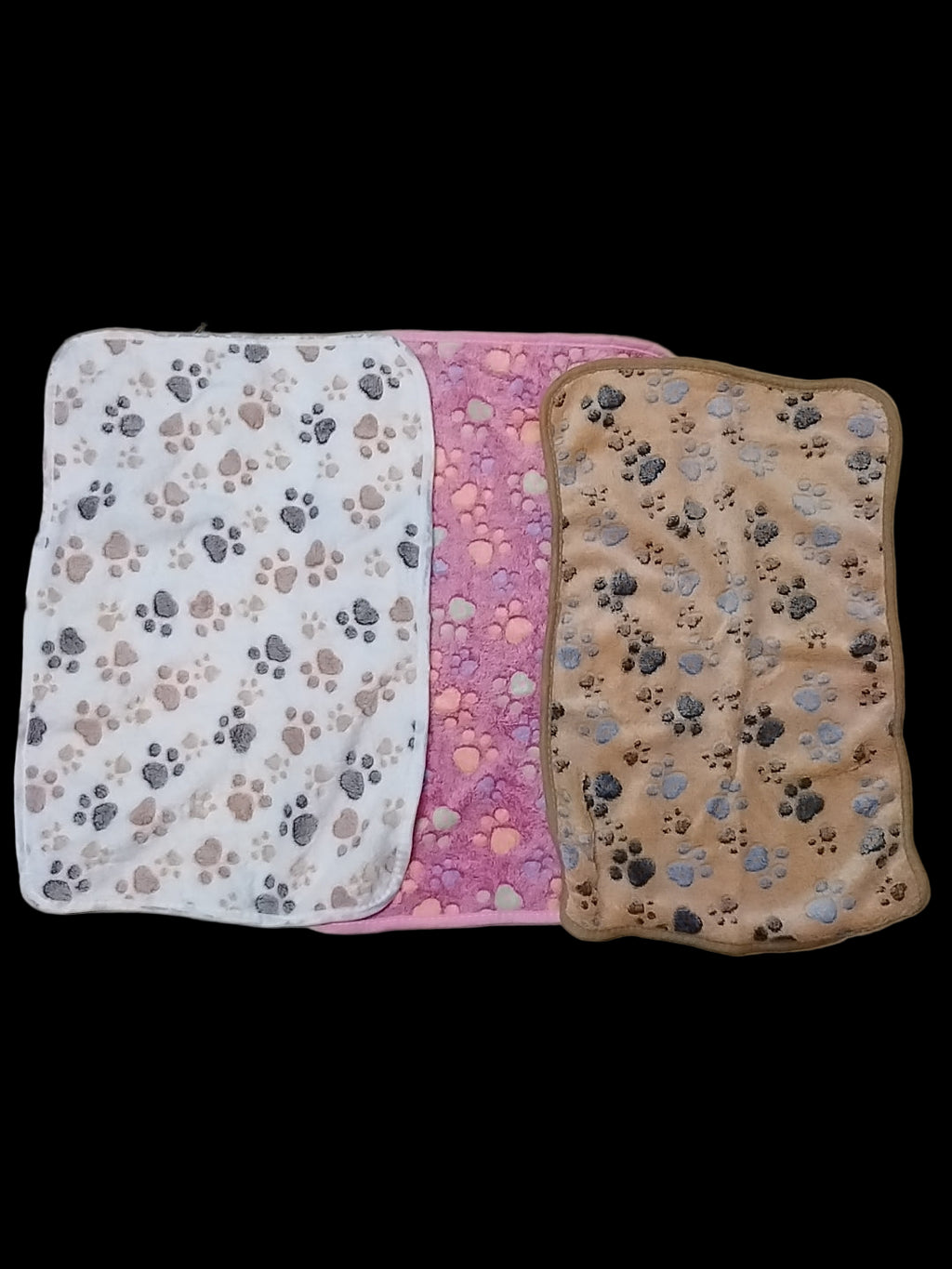Three pet blankets with paw print patterns on a tiled floor.