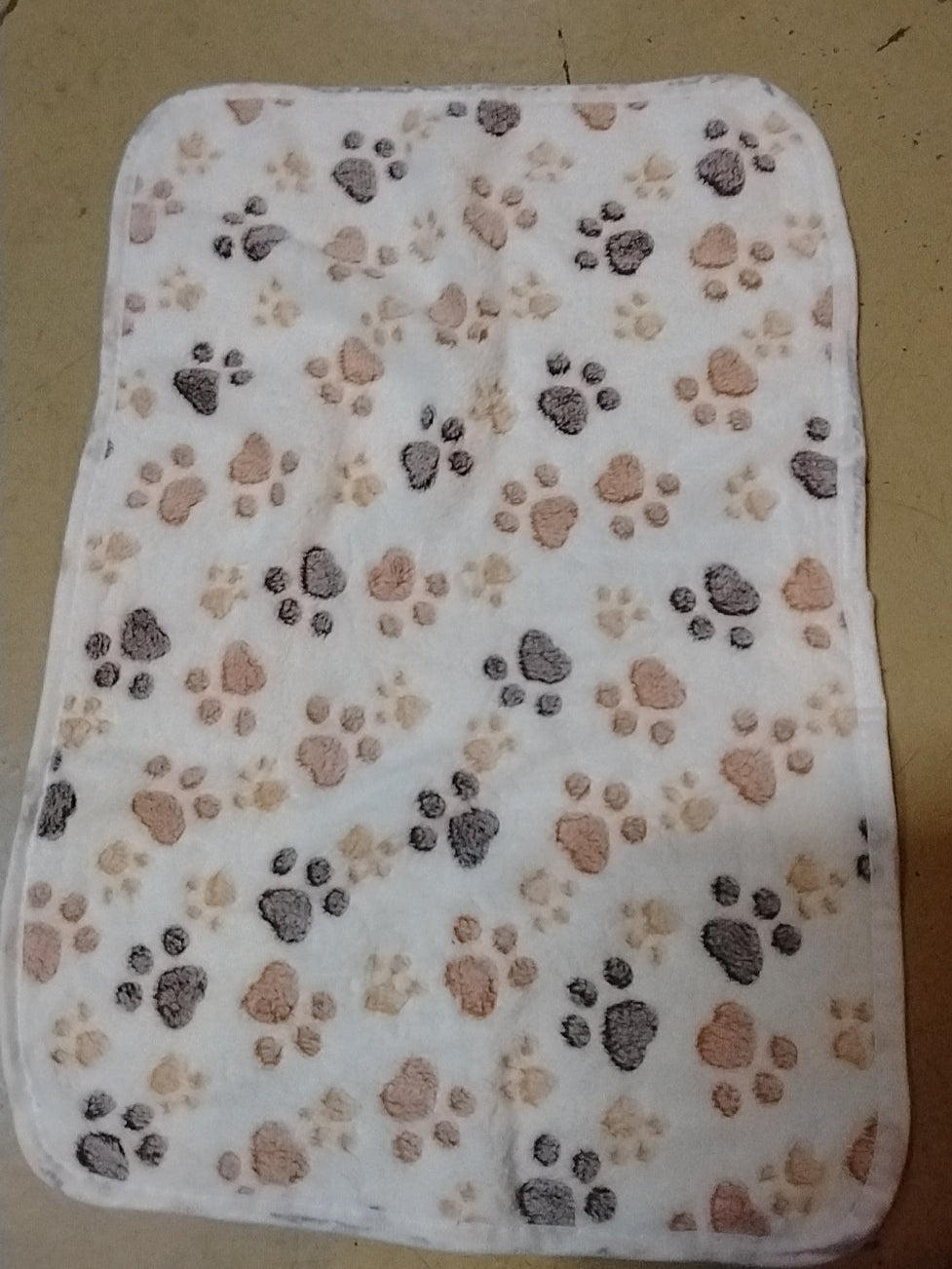 Flannel blanket with paw print pattern on a beige background