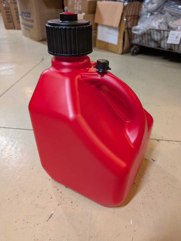 Red fuel container with black cap on a tiled floor