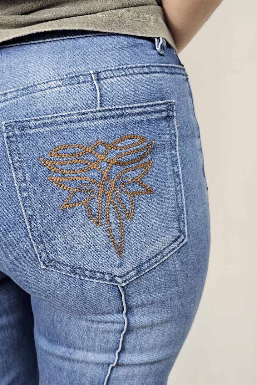 Close-up of blue jeans with a decorative emblem on the back pocket against a neutral background