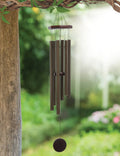 Decorative wind chime hanging from a branch with a blurred garden background