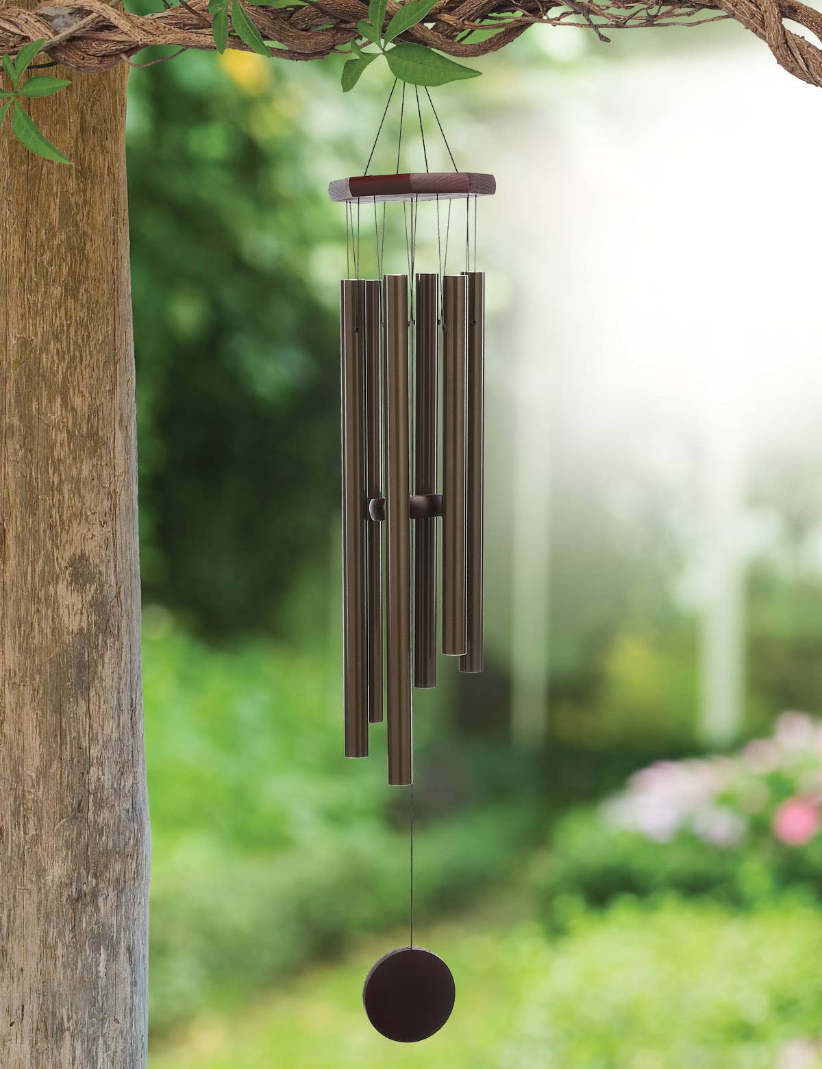 Decorative wind chime hanging from a branch with a blurred garden background