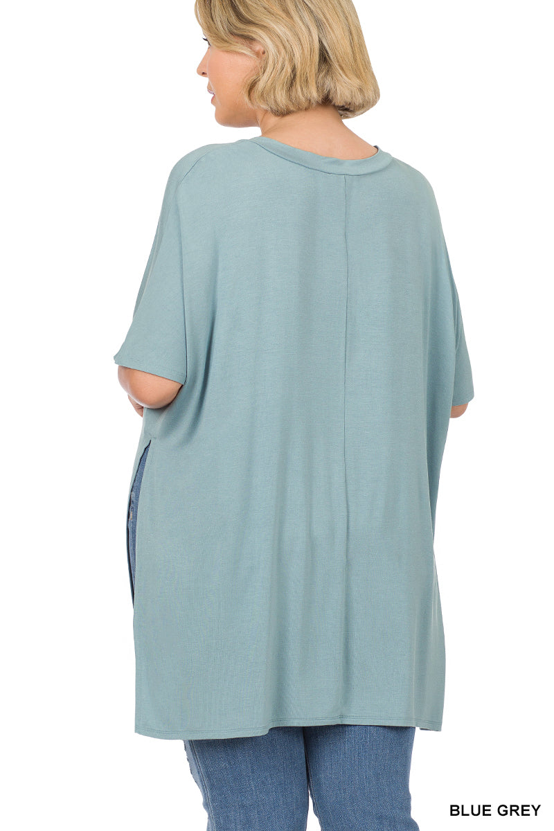 Woman wearing a blue-grey oversized top with a white background
