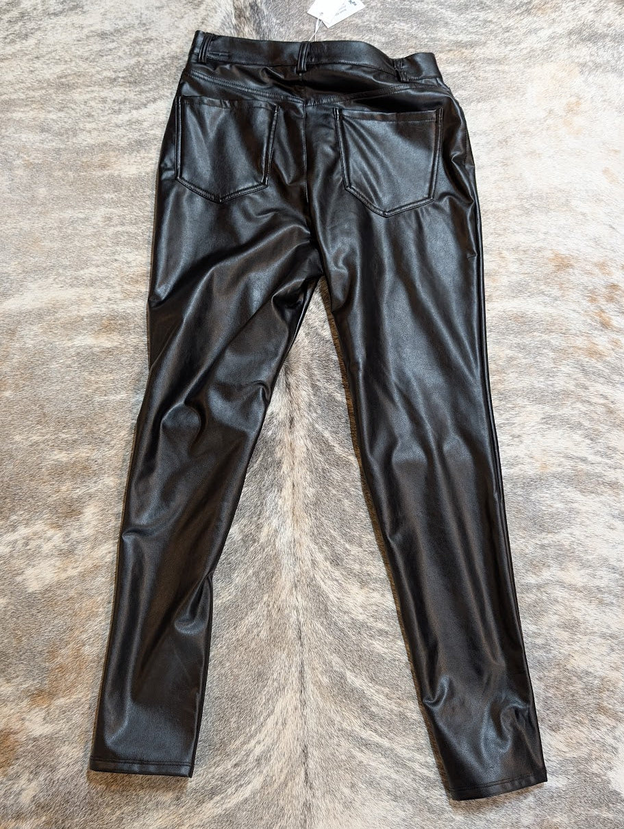 Black leather pants on a textured stone surface