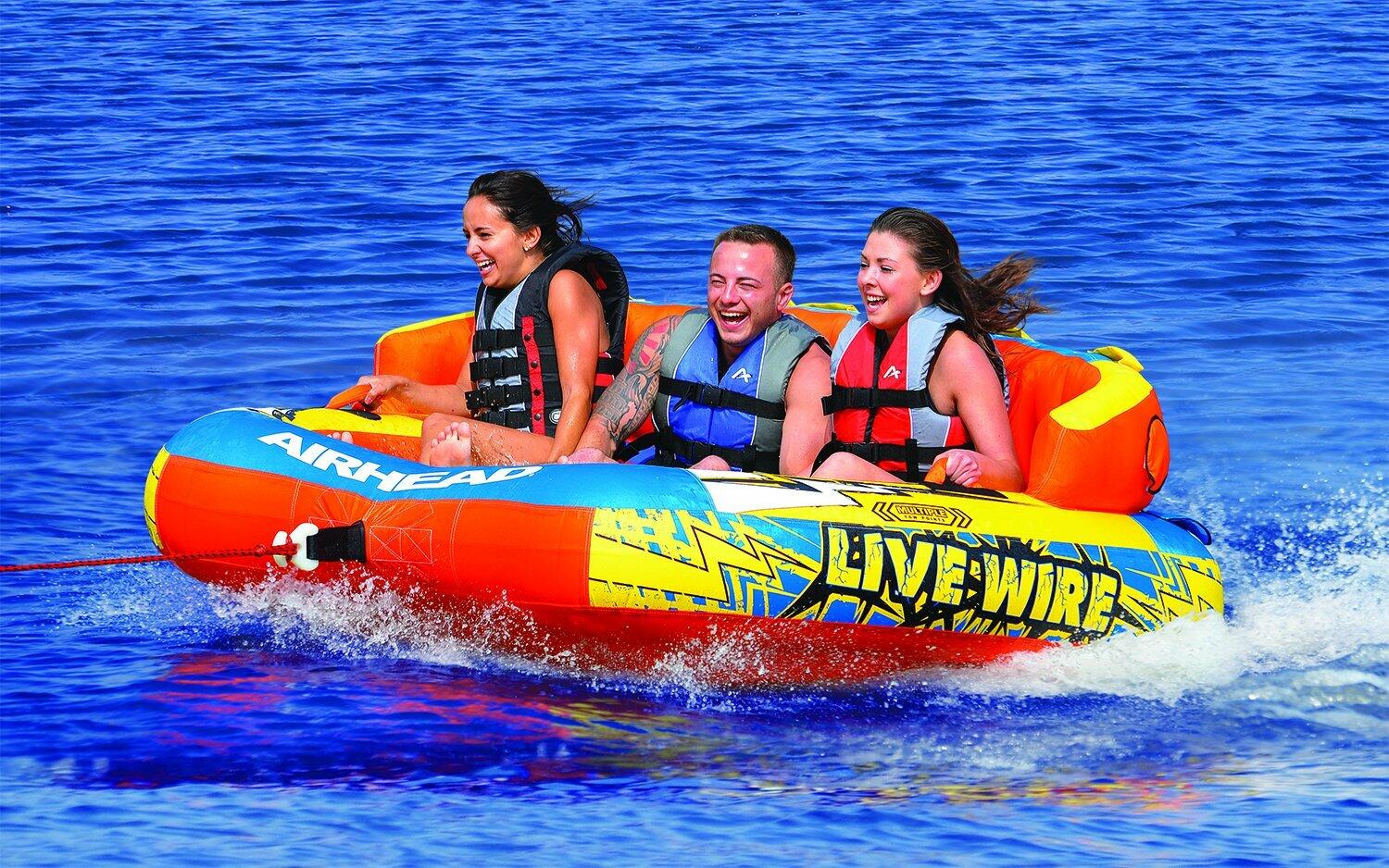 Three people on a colorful live wire inflatable tube in the water
