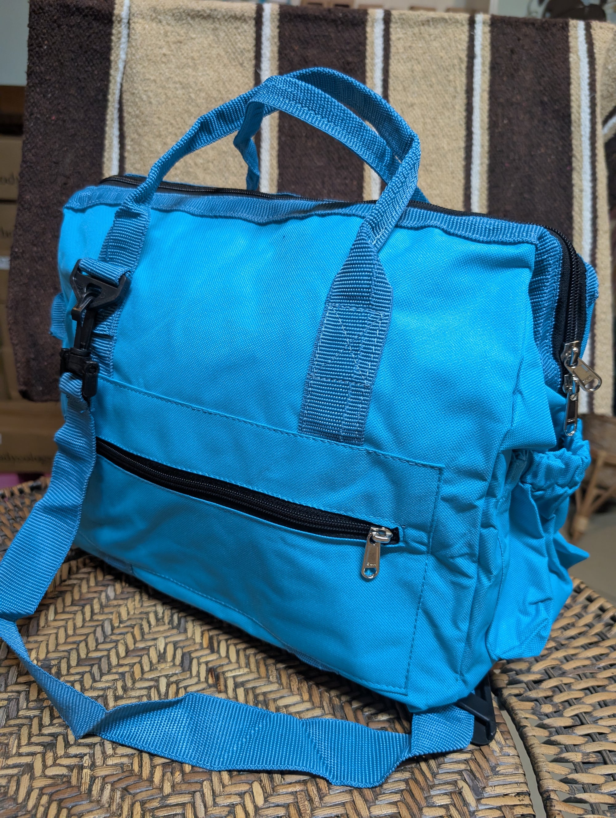 Blue duffel bag with a black zipper on a woven surface