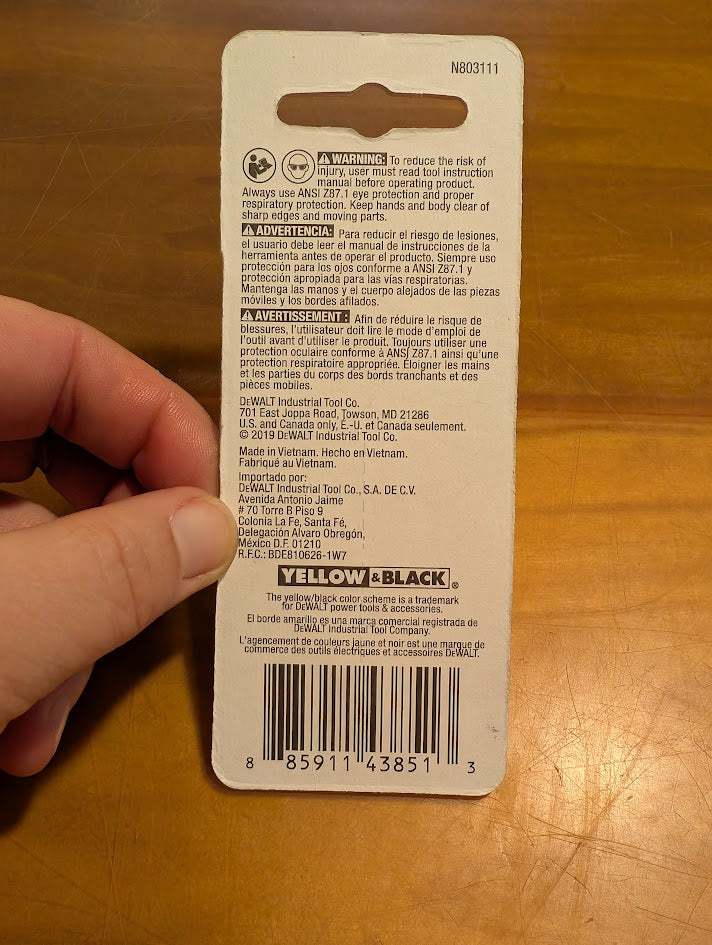 Back of a tool packaging with text and a barcode on a wooden surface