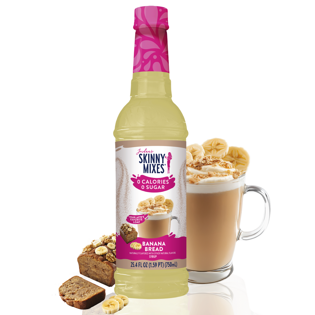 Skinny Mixes banana bread syrup bottle with a glass of coffee and banana bread slices on a white background