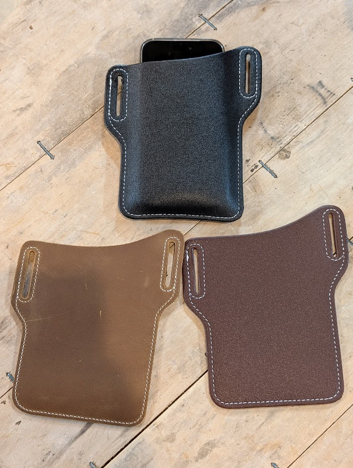 three belt style cell phone holsters on wood background