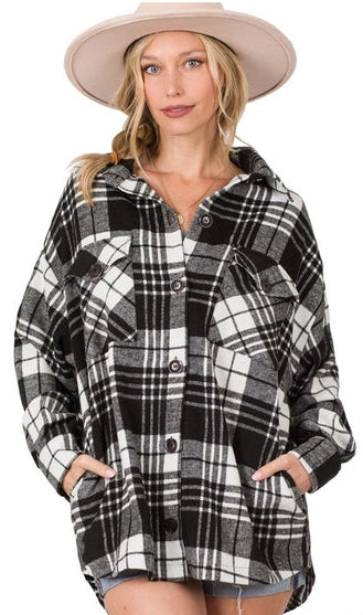Woman wearing a black and white plaid shirt with a beige hat on a white background