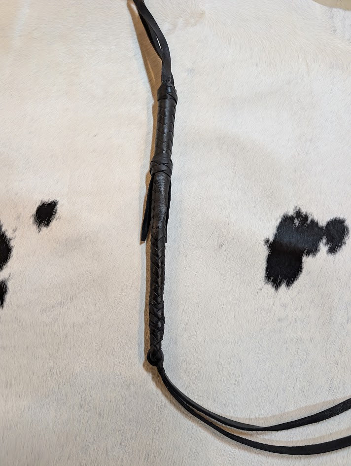 Black Leather braided whip on a black and white cowhide