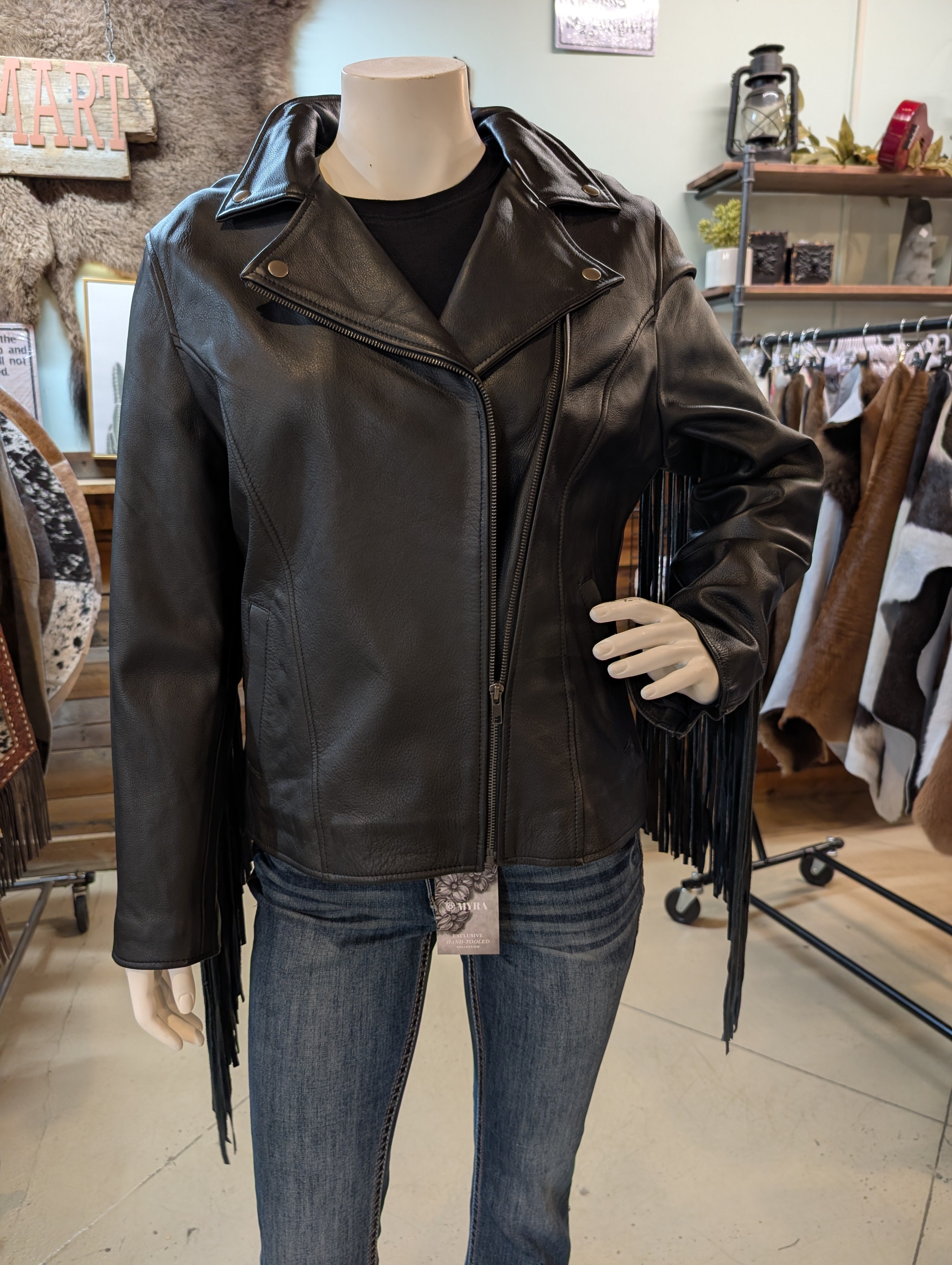 Black leather jacket with fringe on a mannequin in a store setting