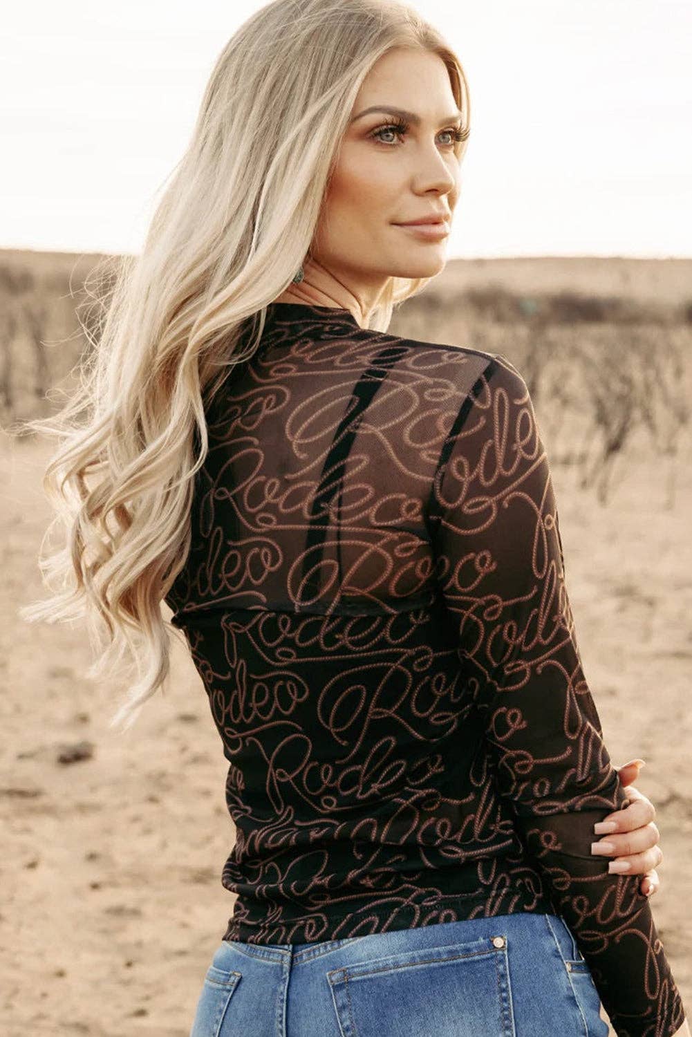Woman wearing a black patterned top with a blurred desert background