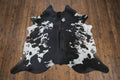 Black and white cowhide rug on a rustic wood floor