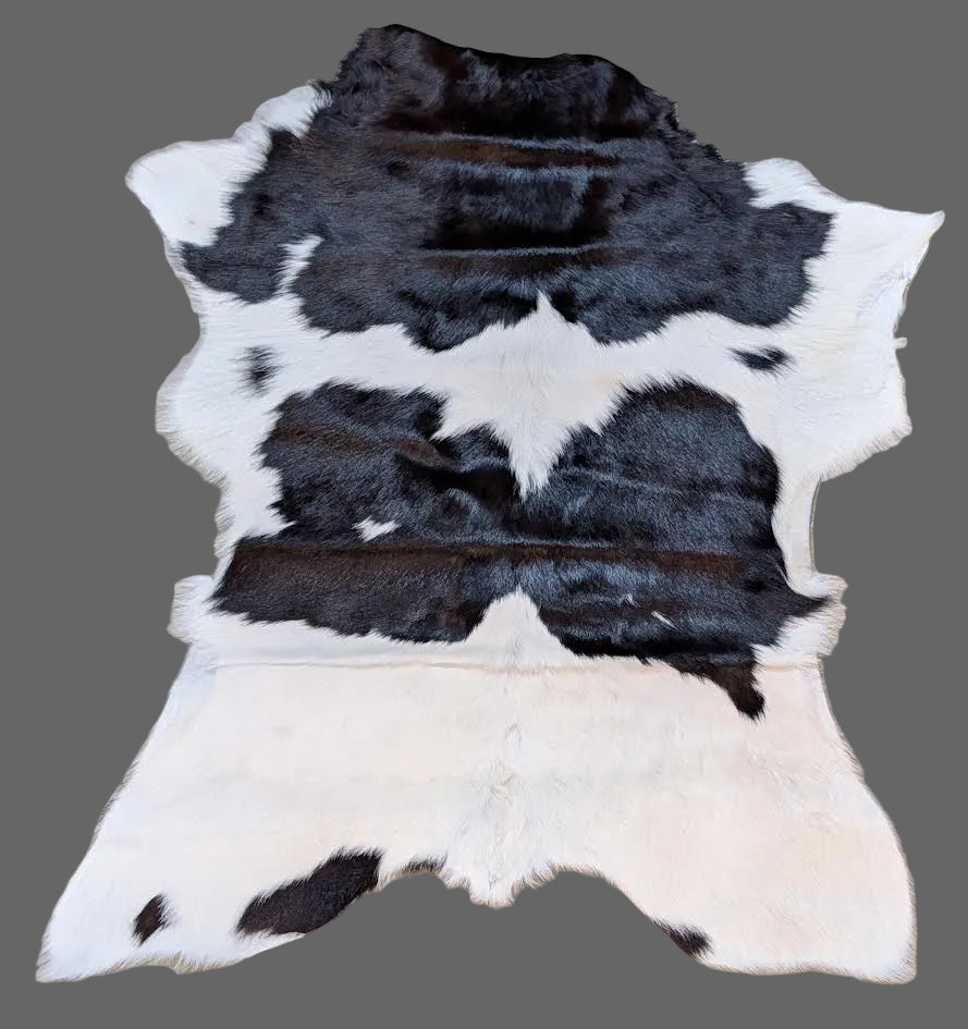Black, white, and brown cowhide rug on a gray floor.