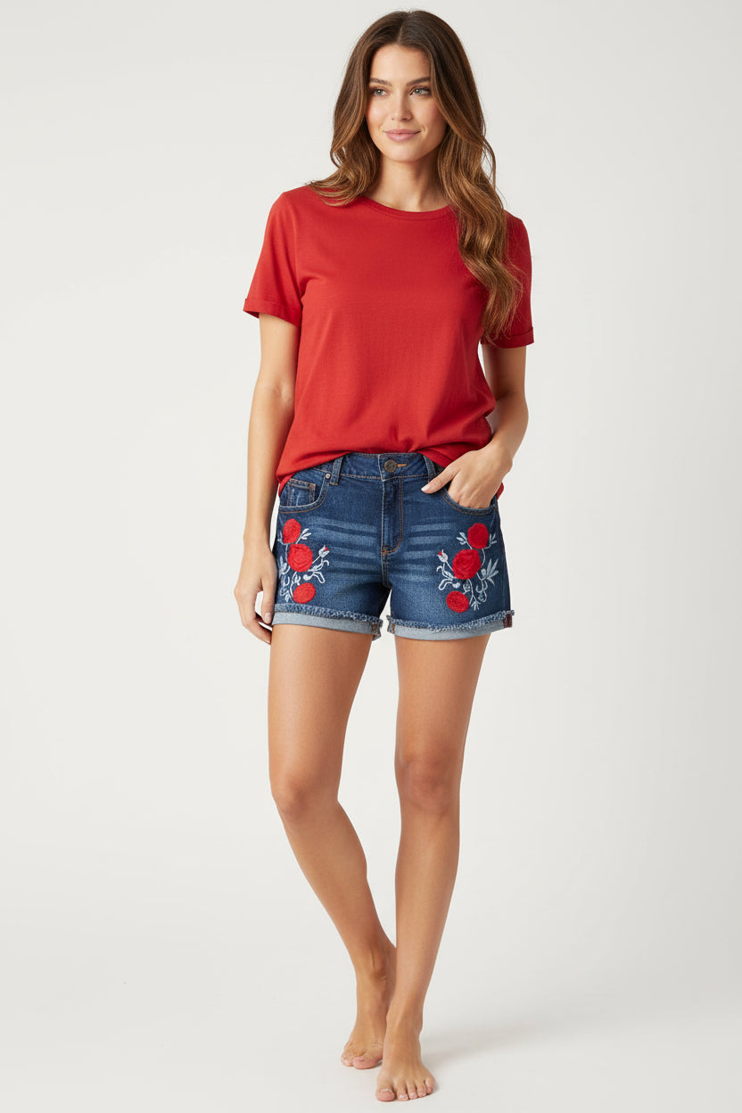 Blue denim shorts with red floral embroidery on a white surface