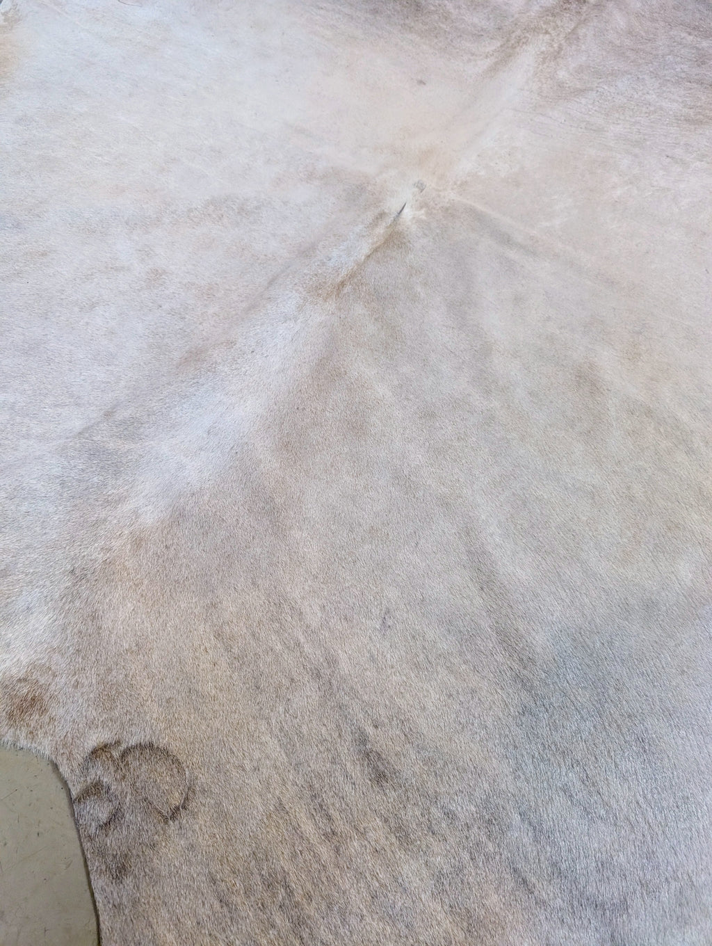 Large natural cowhide hide with branding mark and soft neutral color palette