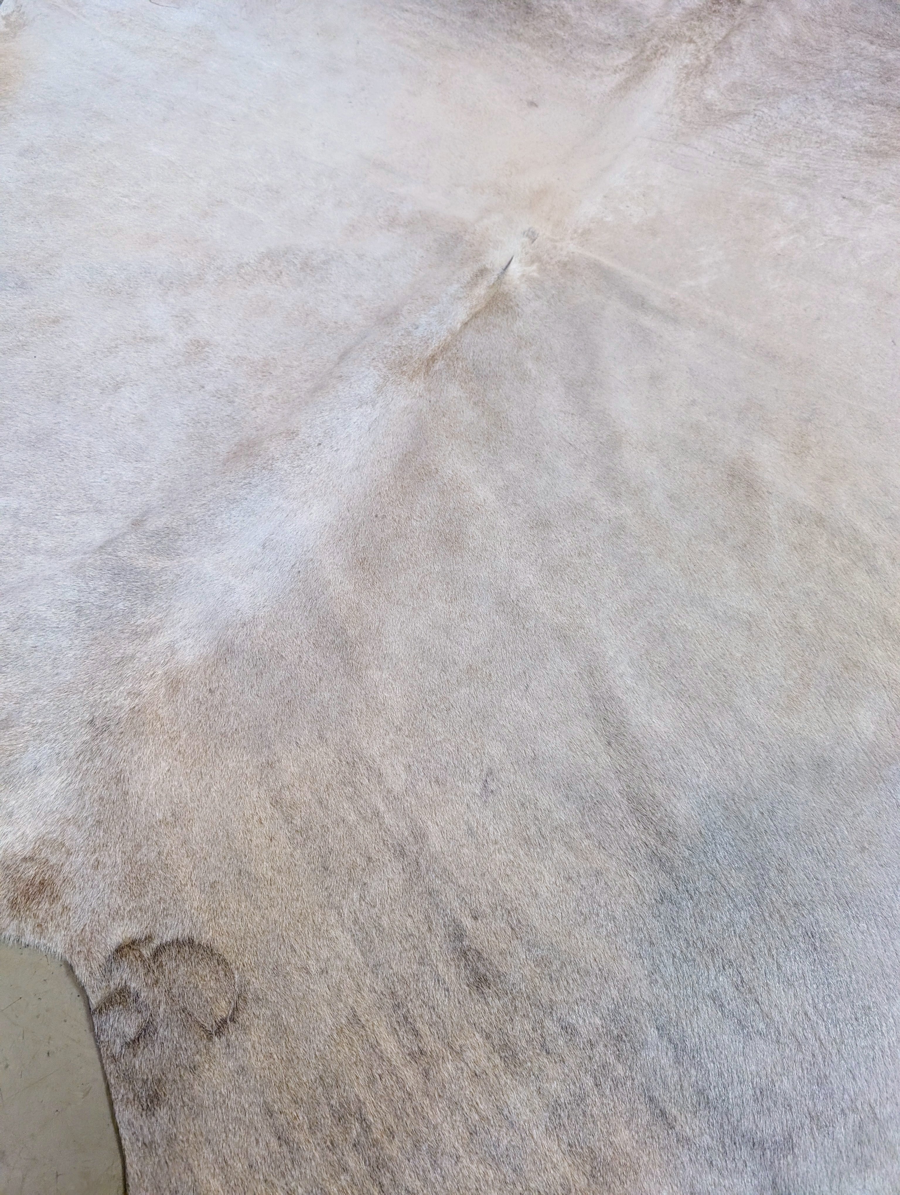 Large natural cowhide hide with branding mark and soft neutral color palette