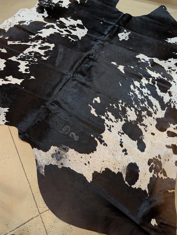 Up-close of black and white cowhide rug with brands on a tan floor