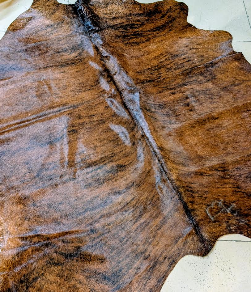 Close-up brindle cowhide rug on a tan floor. 