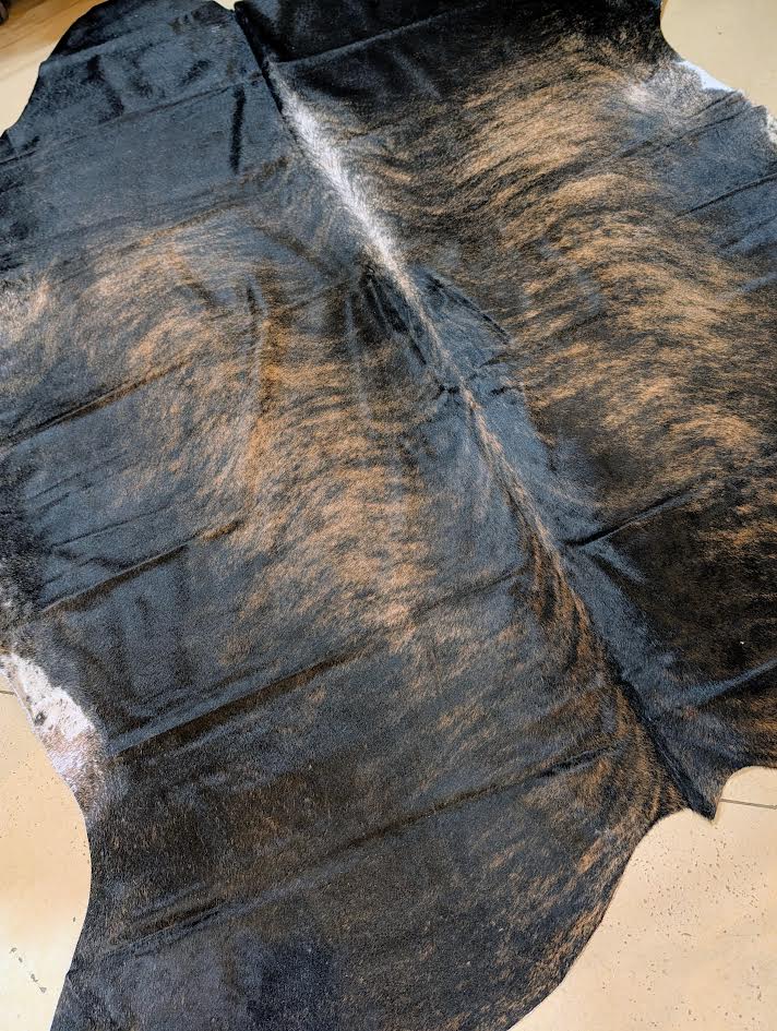 Close-up of a dark-colored cowhide rug on a light background