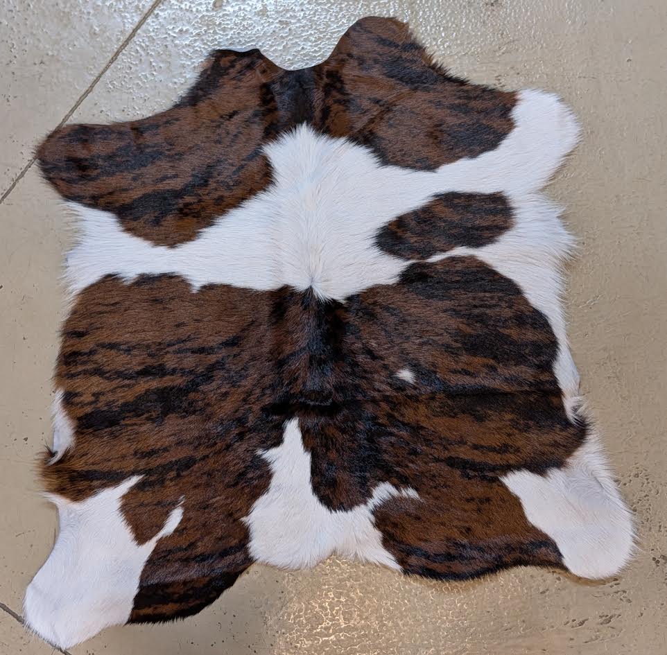 Brown and white cowhide rug on a beige floor.