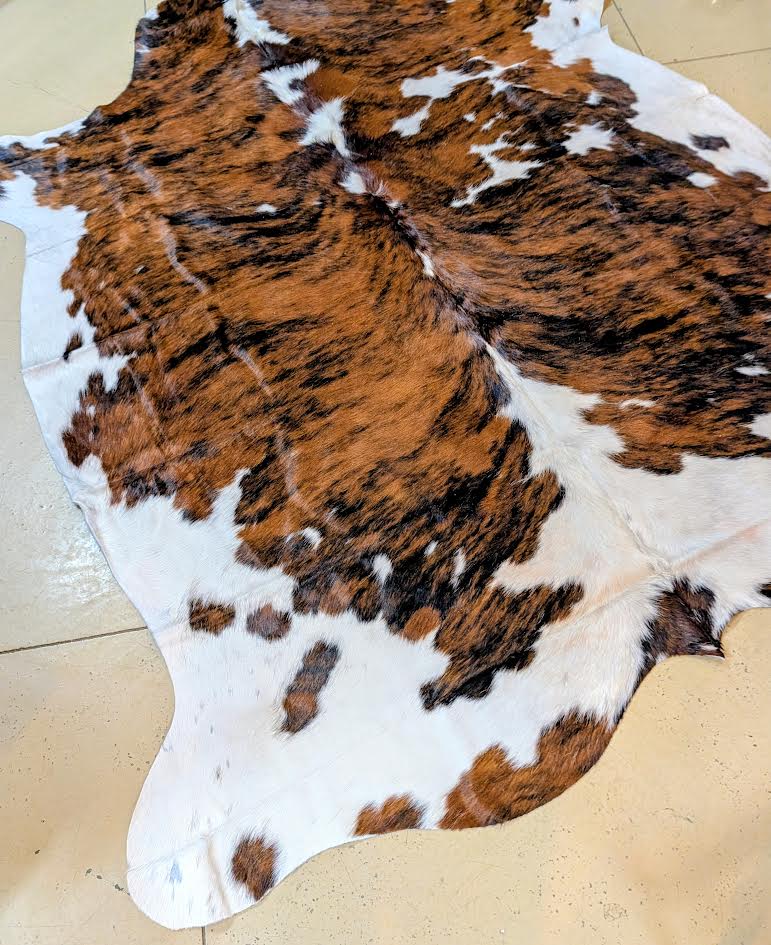 Brown, white, and black cowhide rug on a beige floor.