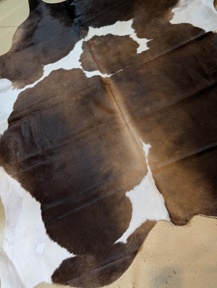 Brown and white cowhide rug on a concrete floor