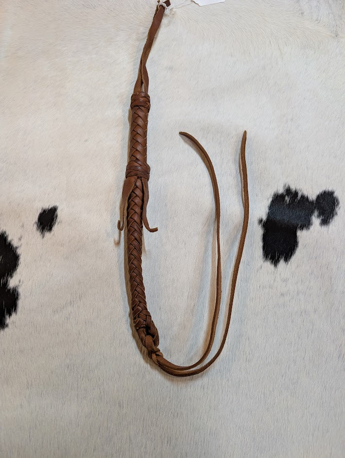 Brown leather whip on a black and white cowhide rug