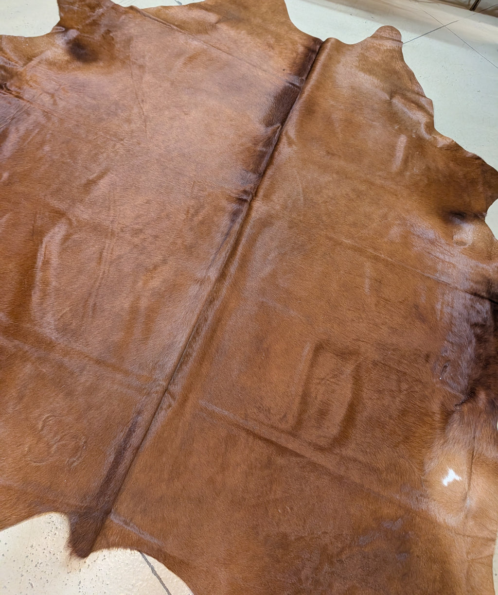 Brownish/red cowhide rug on a tan floor